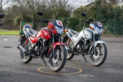 A red motorbike and a silver motorbike, both with L plates, parked side by side on the practice area.