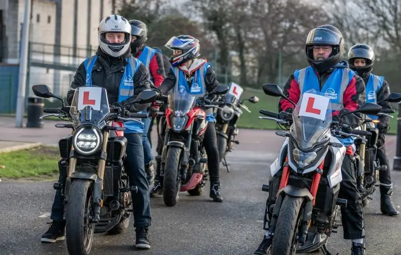 A row of learner riders in blue Bikes in Motion student vests, sitting on motorbikes with L plates ready to start a training session.